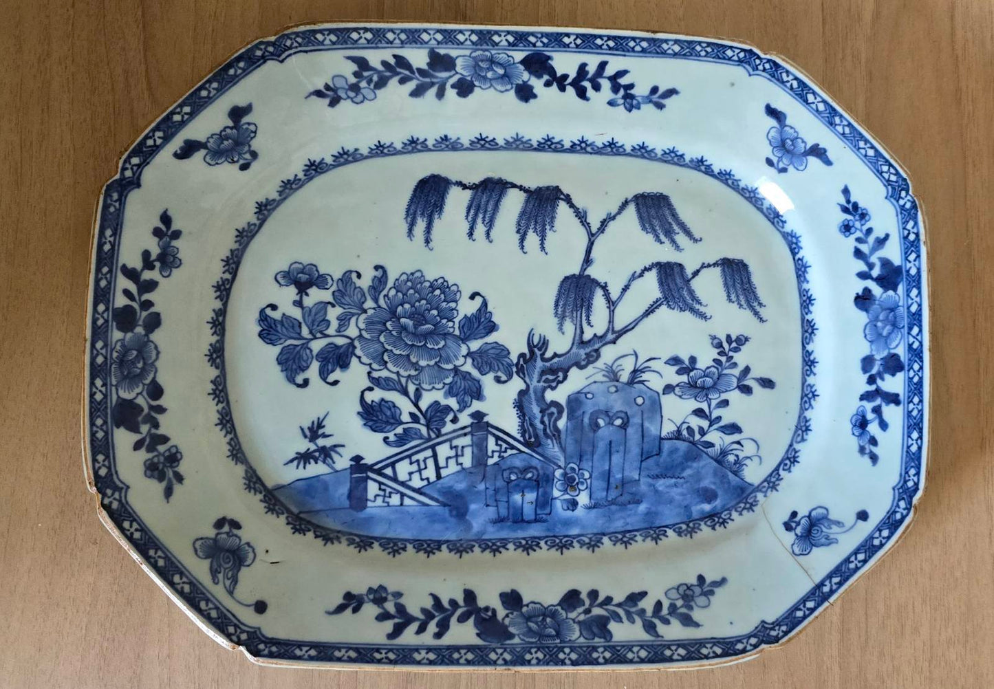 A blue and white plate featuring a detailed garden scene, showcasing flowers and greenery in a serene design.