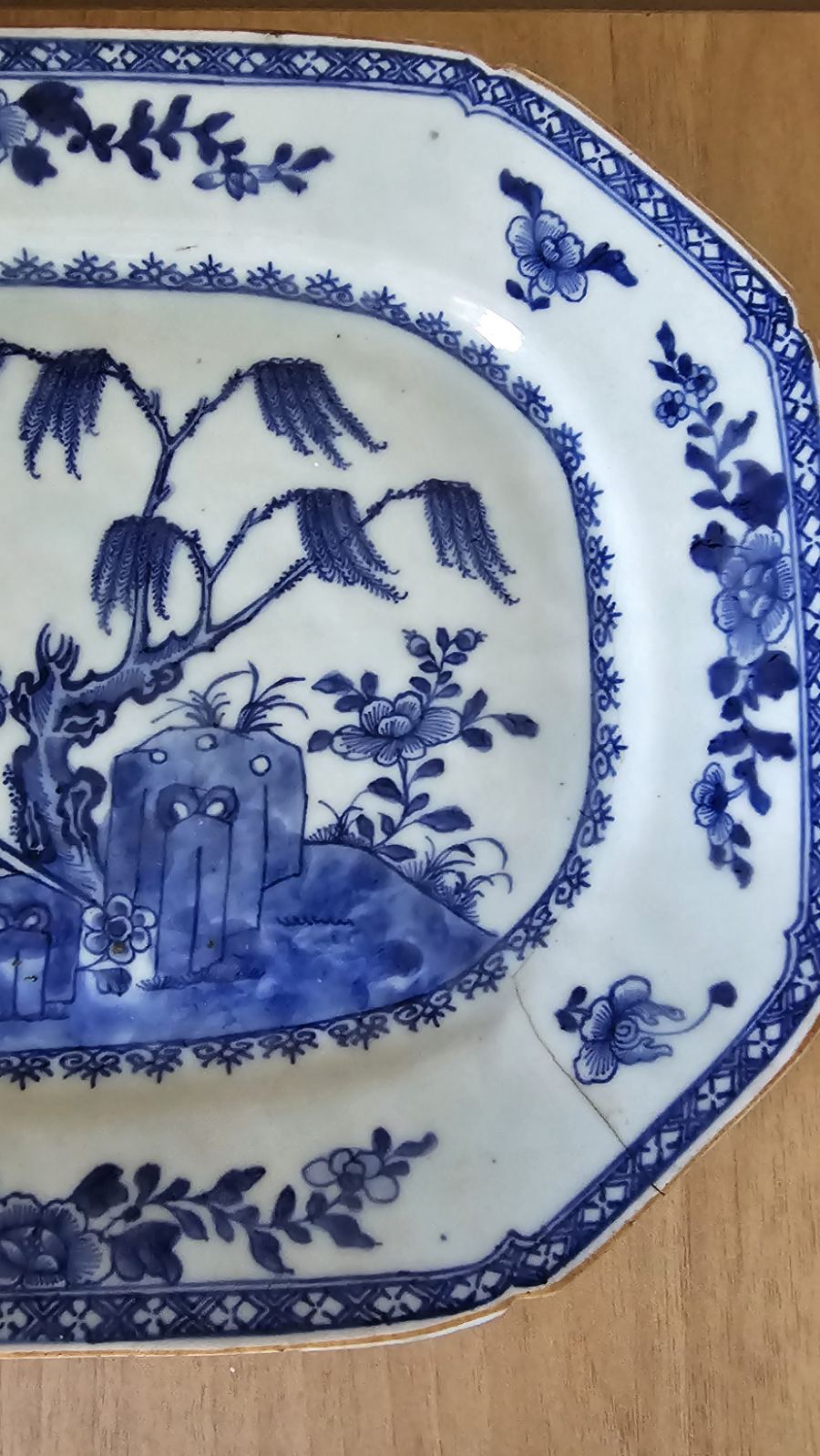 A blue and white plate featuring a detailed garden scene, showcasing flowers and greenery in a serene design.