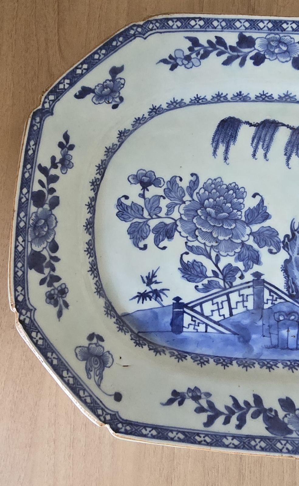 A blue and white plate featuring a detailed garden scene, showcasing flowers and greenery in a serene design.